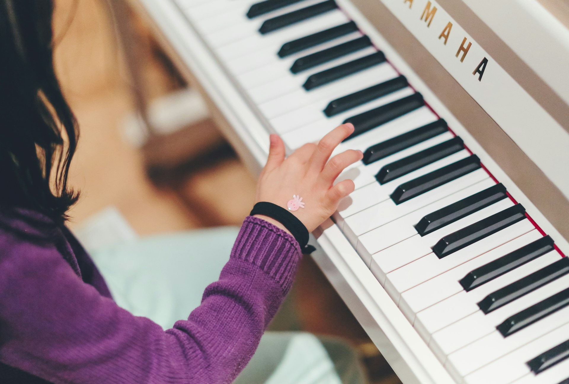 Child sitting at a piano with fingers on the keys